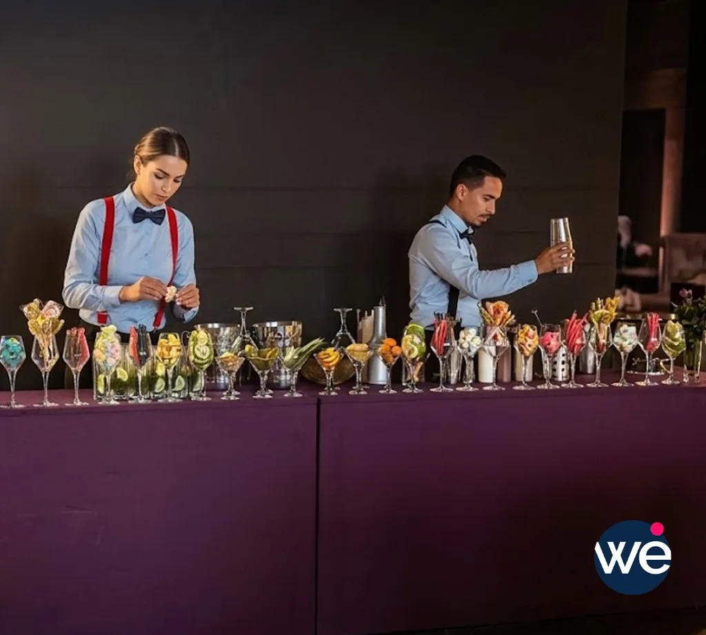 Barmen professionnels en uniforme préparant des cocktails artisanaux derrière un comptoir garni lors d'une soirée événementielle au Maroc