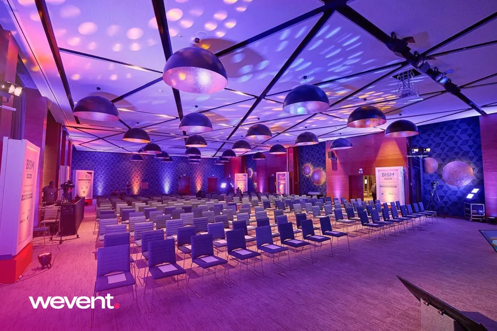 Salle plénière BISM au Maroc : configuration congrès avec éclairage scénique bleu et violet, rangées de sièges et scène équipée